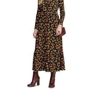 May include: A long-sleeved black dress with a yellow floral pattern. The dress has a tiered skirt and a tie detail at the neckline. The model is wearing brown ankle boots.