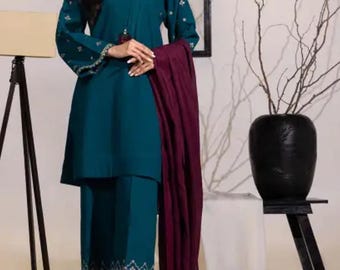 May include: A teal blue long-sleeved top with embroidered details and matching pants. The top has a high neckline and a long, flowing burgundy scarf.