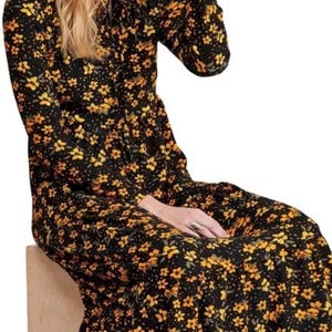 May include: Black long-sleeve dress with a yellow floral pattern. The dress has a high neckline and a flowing skirt. The floral print is composed of small, yellow flowers with green leaves. The dress appears to be made of a lightweight fabric.