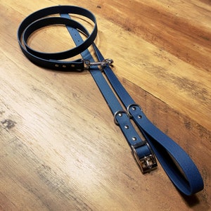 May include: A blue leather dog collar and lead set with silver hardware. The collar has a buckle closure and the lead has a clip.