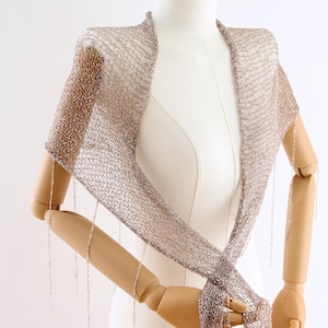 Hand knitted silver sequin shawl displayed on a mannequin, showing the delicate texture and elegant drape of the wrap.