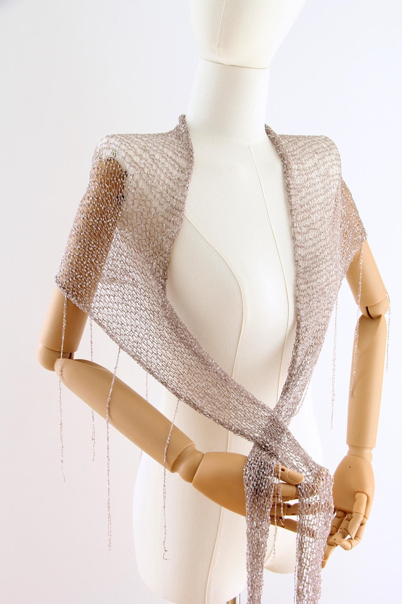 Hand knitted silver sequin shawl displayed on a mannequin, showing the delicate texture and elegant drape of the wrap.