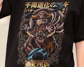May include: Black t-shirt featuring a colorful graphic of a pirate character with the text "ONE PIECE" and Japanese text. The design includes chains, a pirate hat, and a skull. The shirt is worn by a person wearing black sunglasses.