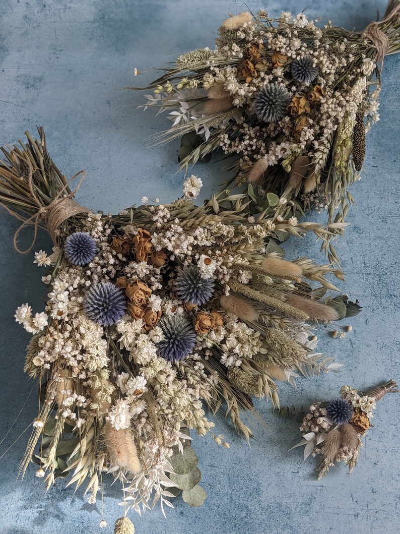 Puede incluir: Un conjunto de tres ramos de flores secas en tonos blancos, beige y azules. Los ramos est&aacute;n hechos con hierbas secas, flores y eucalipto.