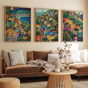 May include: Three framed colorful paintings depicting a tropical island town with buildings, palm trees, and a blue ocean. The paintings are hanging on a wall above a brown sectional sofa with striped throw pillows.