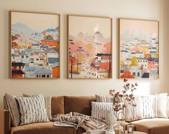 May include: A brown sectional sofa with a throw blanket and cushions in a living room with three framed prints of cityscapes above the sofa. The prints are in a light brown frame and feature a watercolour style.