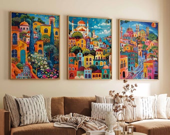 May include: Three colorful paintings depicting scenes of buildings in a city. The paintings are framed in wood and hung on a wall above a brown couch with pillows.