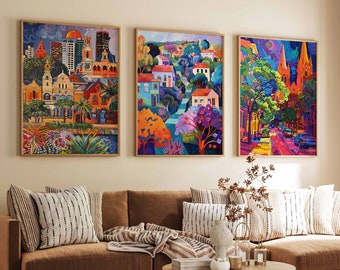 May include: Three colorful paintings of cityscapes with buildings, trees, and streets. The paintings are framed in wood and hung on a wall above a brown sectional sofa.