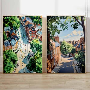 May include: Two framed watercolor paintings of cityscapes. One depicts a street scene from above, with buildings, trees, and people. The other shows a street with buildings, trees, and a blue sky. Both are in gold frames.