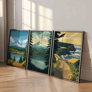 May include: Three framed landscape art prints. The artwork depicts mountain scenes with lakes, forests, and coastal views. The color palette includes blues, greens, and yellows. Each print is in a black frame, leaning against a white wall.