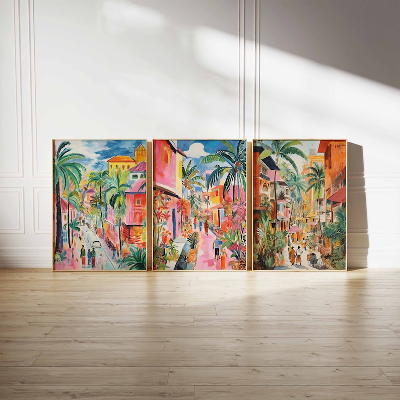 May include: A three-piece set of colorful paintings depicting a street scene in a tropical city. The paintings feature vibrant colors, palm trees, and buildings with pink and yellow accents. The paintings are framed in gold.