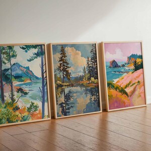 May include: Three framed landscape paintings with wooden frames. The paintings depict serene scenes of nature, including mountains, lakes, and coastal views. The color palettes feature blues, greens, pinks, and yellows, creating a calming and artistic aesthetic.