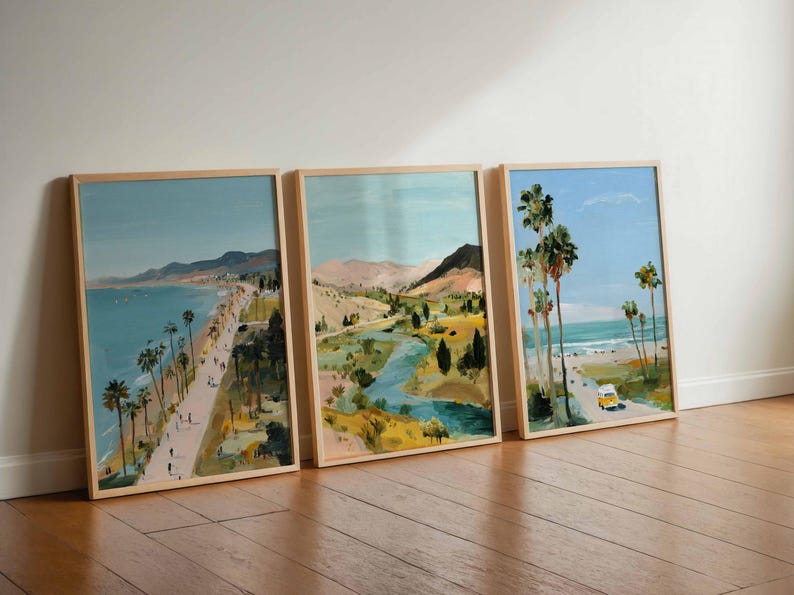 May include: Three framed landscape art prints. The artwork depicts coastal scenes with palm trees, beaches, and roads. The color palette includes blues, greens, and yellows, with a wooden frame.