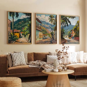 May include: Three framed paintings depicting colorful scenes of tropical towns with palm trees, lush greenery, and mountain ranges in the background.