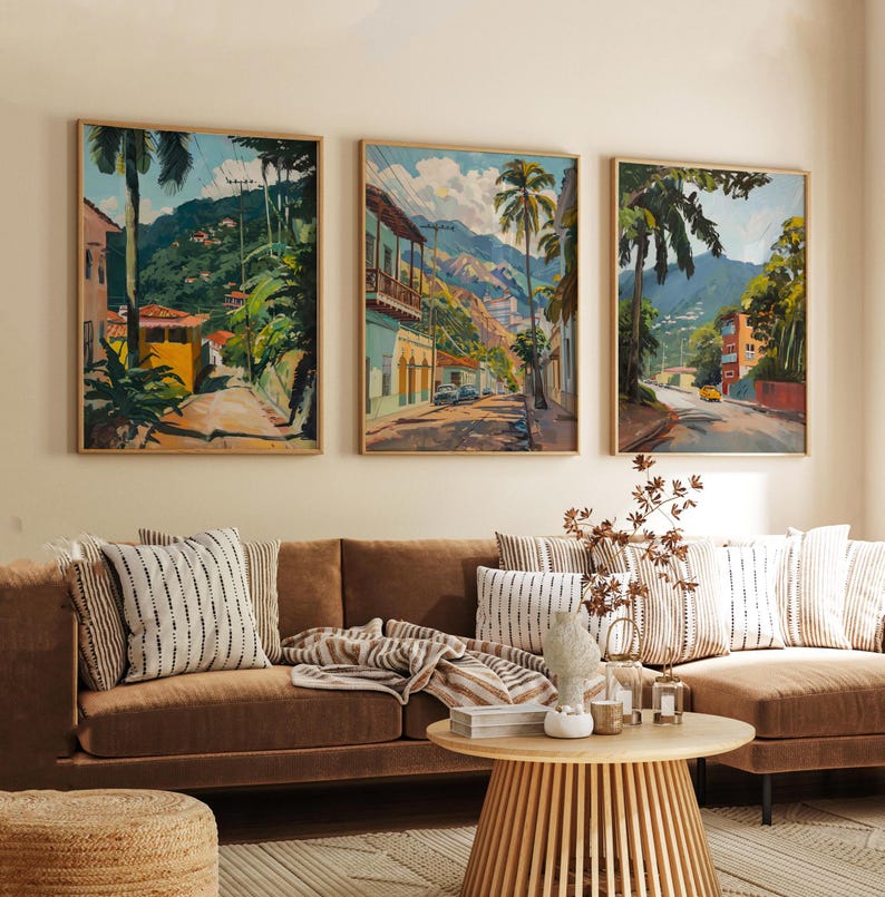 May include: Three framed paintings depicting colorful scenes of tropical towns with palm trees, lush greenery, and mountain ranges in the background.