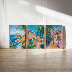 May include: Three framed paintings depicting a colorful seaside town with palm trees, buildings, and a winding road. The paintings are in a modern style with bright colors and bold lines.