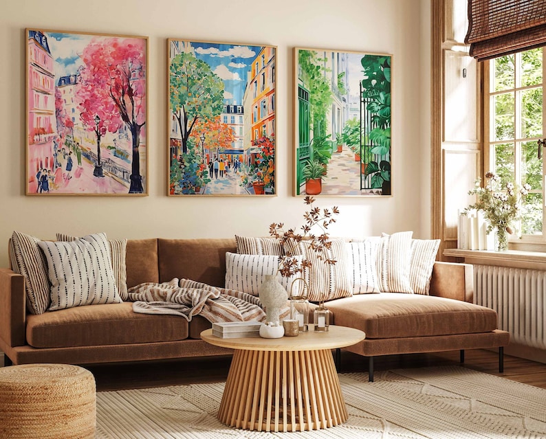 K&ouml;nnte beinhalten: Ein braunes Ecksofa mit drei Kissen und einem Holz-Couchtisch davor. Drei gerahmte Bilder von Stadtansichten h&auml;ngen an der Wand hinter dem Sofa.