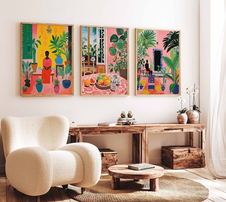 May include: Three framed illustrations of tropical scenes with vibrant colors and lush greenery. The first image features a woman in a pink dress standing in a room with plants. The second image shows a table with fruit and a vase of flowers. The third image depicts a person sitting in a room with plants and a doorway.