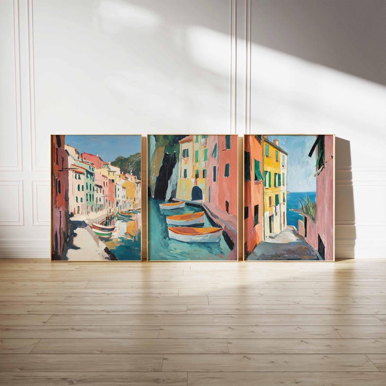 May include: A set of three colorful paintings depicting a waterfront scene with buildings, boats, and a blue sky. The paintings are framed in gold.