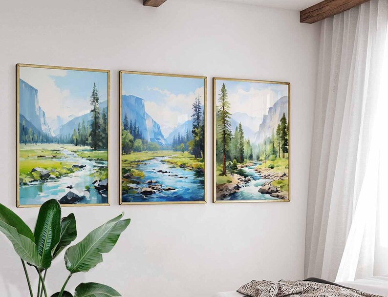 May include: Three framed landscape paintings depicting a river flowing through a valley with mountains and trees. The artwork features a watercolor style with shades of blue, green, and gold. The paintings are displayed on a white wall.