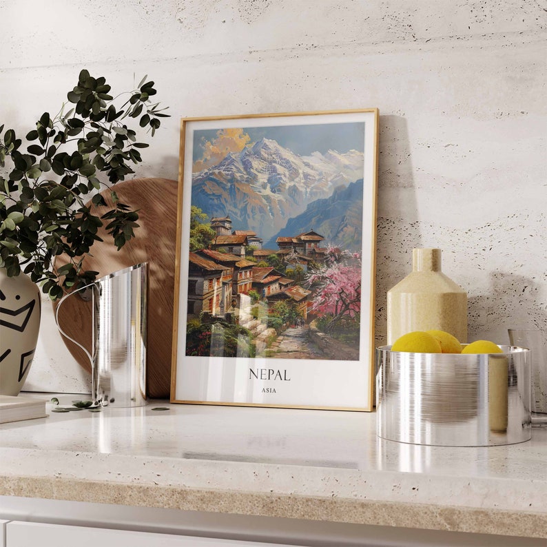 May include: A framed vintage travel poster with a picture of a mountain village in Nepal. The poster has a gold frame and the text "Nepal Asia" at the bottom.
