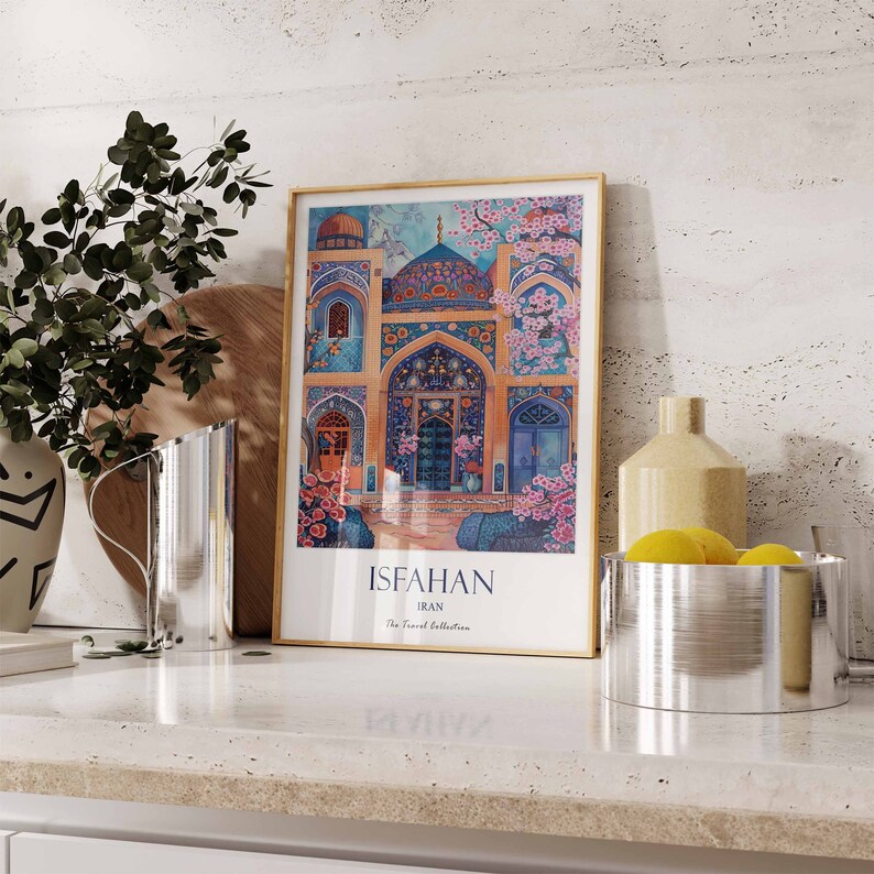 May include: A framed print of a colourful illustration of a mosque in Isfahan, Iran. The print has a gold frame and the text "Isfahan, Iran, The Travel Collection" is printed below the illustration.