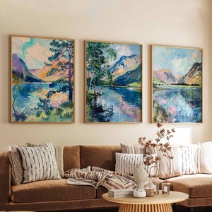 Könnte beinhalten: Drei gerahmte Landschaftsbilder in Blau- und Grüntönen. Die Bilder zeigen einen See mit Bergen im Hintergrund. Die Bilder hängen an einer Wand in einem Wohnzimmer.