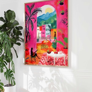 May include: A colorful painting of a pink building with a view of a mountain range and a palm tree. The painting is framed in a wooden frame.