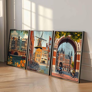 Pu&ograve; includere: Tre stampe artistiche incorniciate raffiguranti scene di Amsterdam. L'opera presenta edifici colorati, canali, un mulino a vento e ciclisti. Le stampe sono esposte su un pavimento in legno, appoggiate a una parete bianca e sono incorniciate in nero.