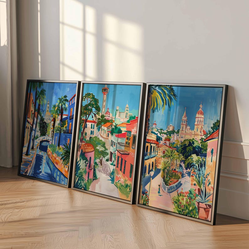 May include: Three framed watercolor paintings depicting colorful cityscapes with buildings, palm trees, and a blue sky. The paintings are framed in silver and black.