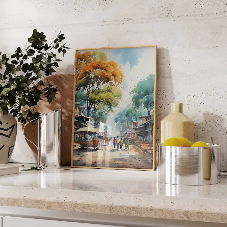 May include: A framed watercolor painting of a street scene in a city. The painting features a street lined with buildings and trees, with people walking along the street. The painting is framed in a gold frame.