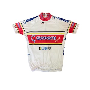 May include: White cycling jersey with a red, yellow and black stripe across the chest. The jersey has the text "Govoni Team" and "Lubritek" printed on it.