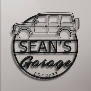 Op de afbeelding: Zwart metalen bord met een silhouet van een auto, de tekst "SEAN'S Garage EST. 2023" en een cirkel eromheen.