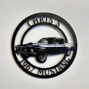 Puede incluir: Arte de pared de metal negro con una silueta de Mustang 1967 con el texto "Chris's 1967 Mustang" alrededor del coche.