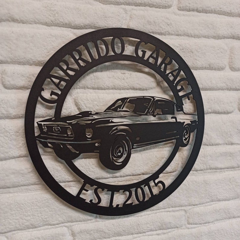 Puede incluir: Placa de metal negro con la silueta de un coche cl&aacute;sico y el texto "Garrido Garage Est. 2015".