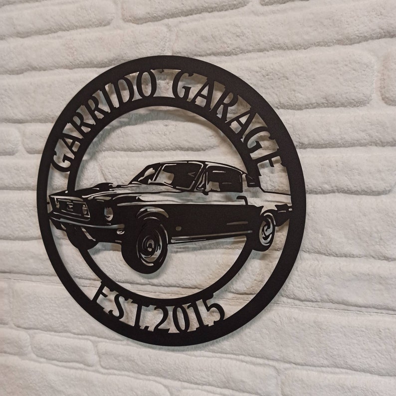 Puede incluir: Placa de metal negro con la silueta de un coche cl&aacute;sico y el texto "Garrido Garage Est. 2015".