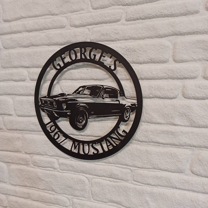 Puede incluir: Placa de metal negro con la silueta de un Ford Mustang de 1967 y el texto "GEORGE'S 1967 MUSTANG".