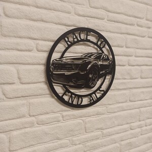 May include: Black metal wall art featuring a silhouette of a car with the text "Race to End Alls" around it.