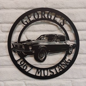 Puede incluir: Arte de pared de metal negro con una silueta de Mustang 1967 con el texto "George's 1967 Mustang" alrededor del coche.