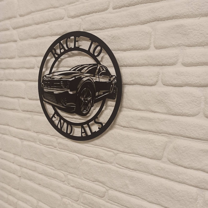 May include: Black metal wall art featuring a silhouette of a car with the words "Race to End Alls" around it.