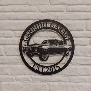 Puede incluir: Placa de metal negro con la silueta de un coche cl&aacute;sico y el texto "Garrido Garage Est. 2015".