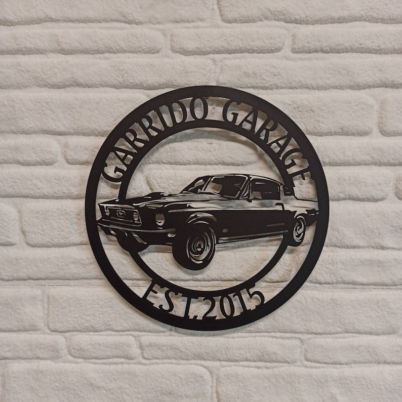 Puede incluir: Placa de metal negro con la silueta de un coche cl&aacute;sico y el texto "Garrido Garage Est. 2015".