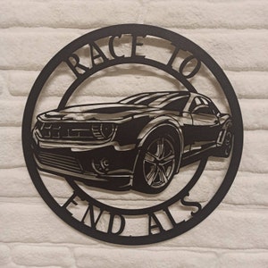 May include: Black metal wall art featuring a silhouette of a car with the words "Race to End" around the outside.