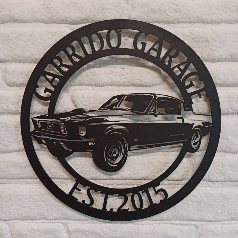 Puede incluir: Se&ntilde;al de metal negro con la silueta de un coche cl&aacute;sico y el texto "Garrido Garage Est. 2015".