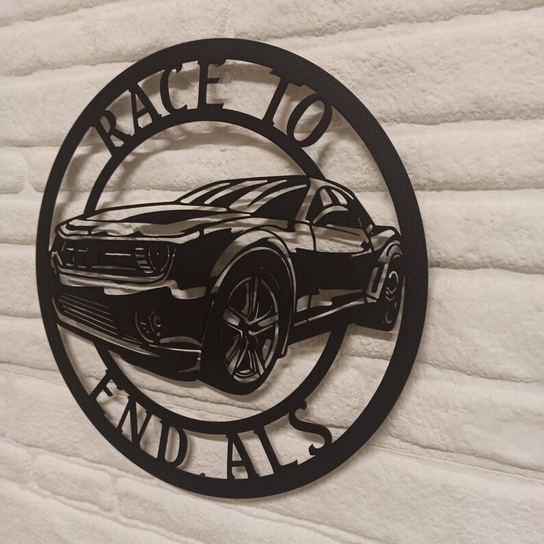 May include: Black metal wall art featuring a silhouette of a car with the words "Race to End Alls" around the perimeter.