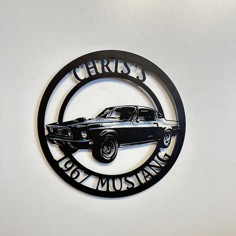 Puede incluir: Arte de pared de metal negro con una silueta de Mustang 1967 con el texto "Chris's 1967 Mustang" alrededor del coche.