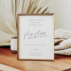 Peut inclure: Un panneau encadré doré avec un fond blanc et du texte noir qui dit "A little treat for your dancing feet flip flops. Please help yourself enjoy Alice and Jacob 20th December 2015".