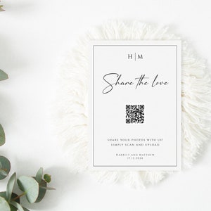 Op de afbeelding: Een witte kaart met zwarte tekst die "HM Share the love" en een QR-code zegt. De tekst onder de QR-code zegt "Share your photos with us! Simply scan and upload Harriet and Matthew 17.12.2014"