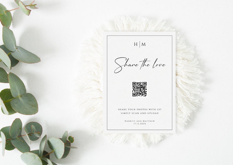 Op de afbeelding: Een witte kaart met zwarte tekst die "HM Share the love" en een QR-code zegt. De tekst onder de QR-code zegt "Share your photos with us! Simply scan and upload Harriet and Matthew 17.12.2014"