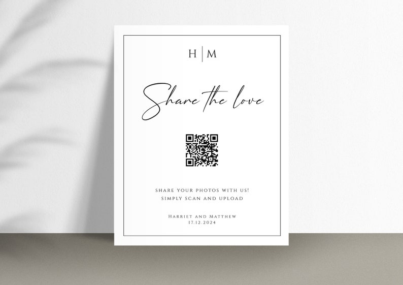 Op de afbeelding: Een wit bord met zwarte tekst die "HM Share the love" en een QR-code zegt. De tekst onder de QR-code zegt "Share your photos with us! Simply scan and upload" en "Harriet and Matthew 17.12.2024".